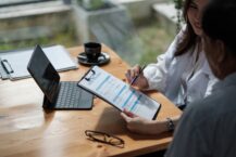 Insurance agent assisting a client with a health insurance application form at a desk